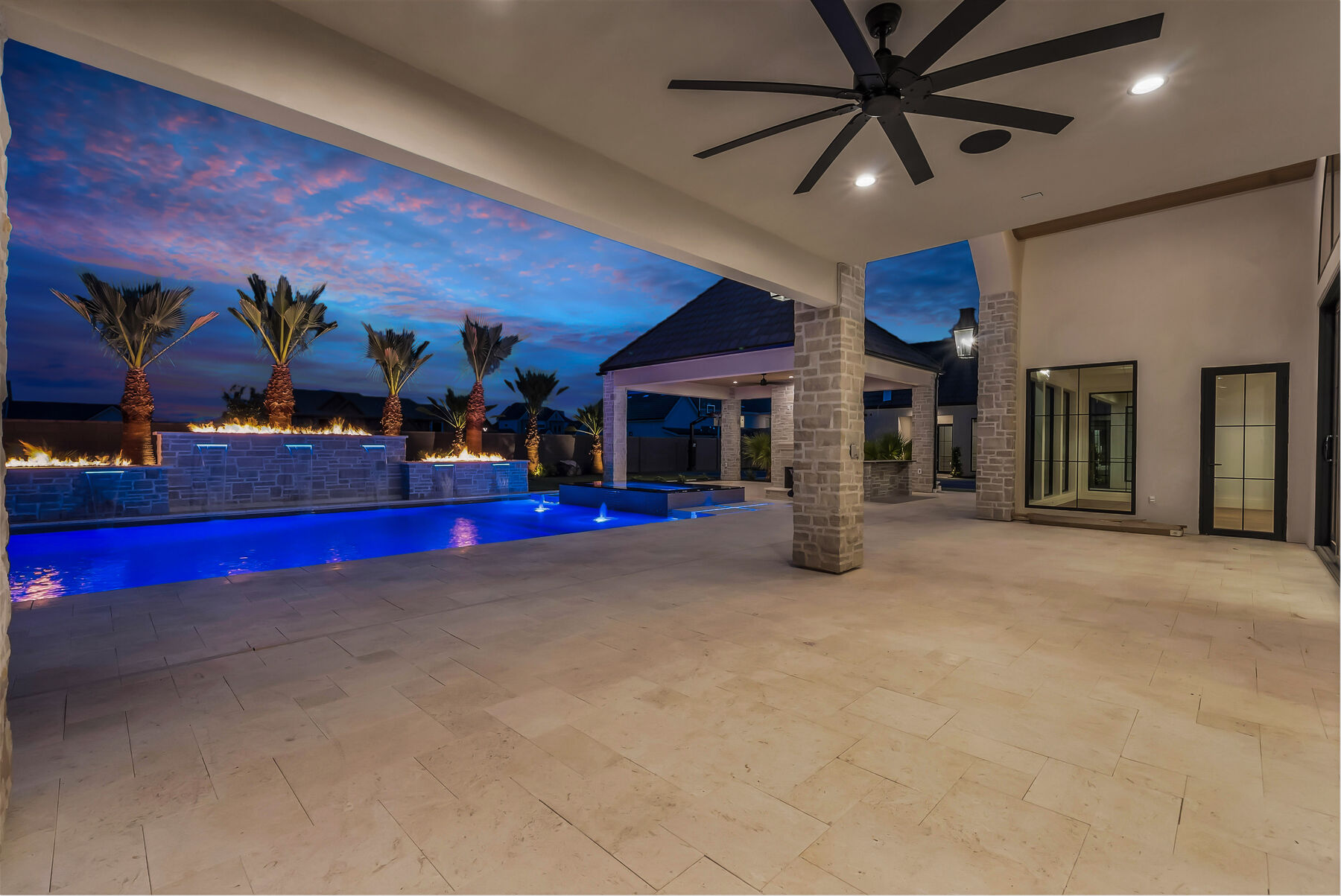 Covered patio looking out to a lit custom pool at twilight — Paragon Pools, St. George